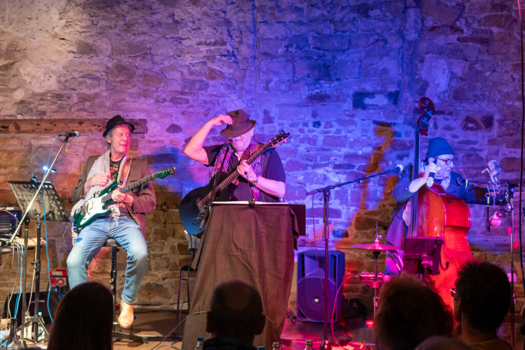 Ein Bild der 3 Musiker der EHL-Band, Eddy hat seinen Hut ins Gesicht gezogen